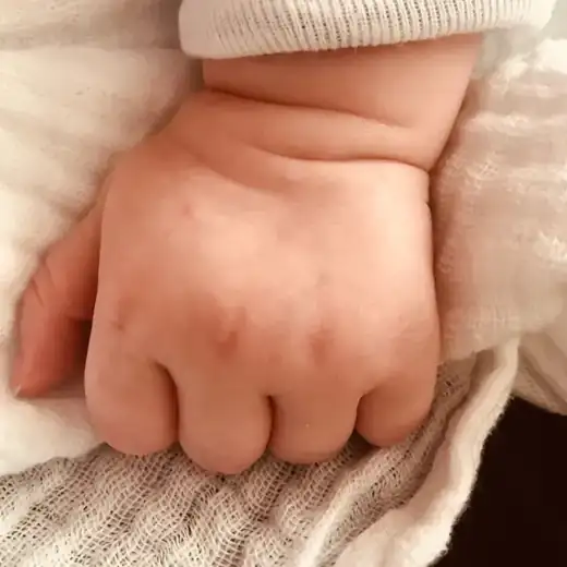 Kleine Babyhand in einem Mulltuch